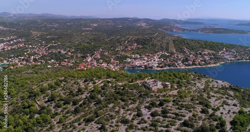 Aerial, orbit, drone shot, around fortress ruins, on the top of mostar hill, overlooking turquoise sea, the coast and the Razanj village, on a sunny, summer day, in Croatia photo