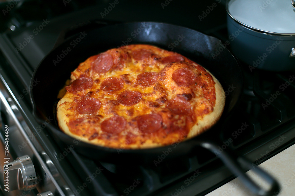 Freshly baked homemade pepperoni pizza in cast iron pan from the oven.
Freshly baked homemade pepperoni pizza in cast iron pan from the oven.