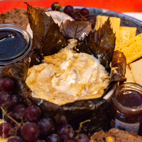 Dessert cheese plate with Castagnino Italian Goat Robiola soft cheese in Chestnut Leaves served with jams and grapes photo