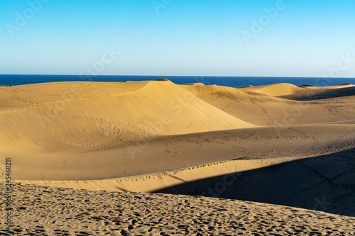 Landscape with yellow sandy dunes of Maspalomas and blue Atlantic ocean, Gran Canaria, Spain