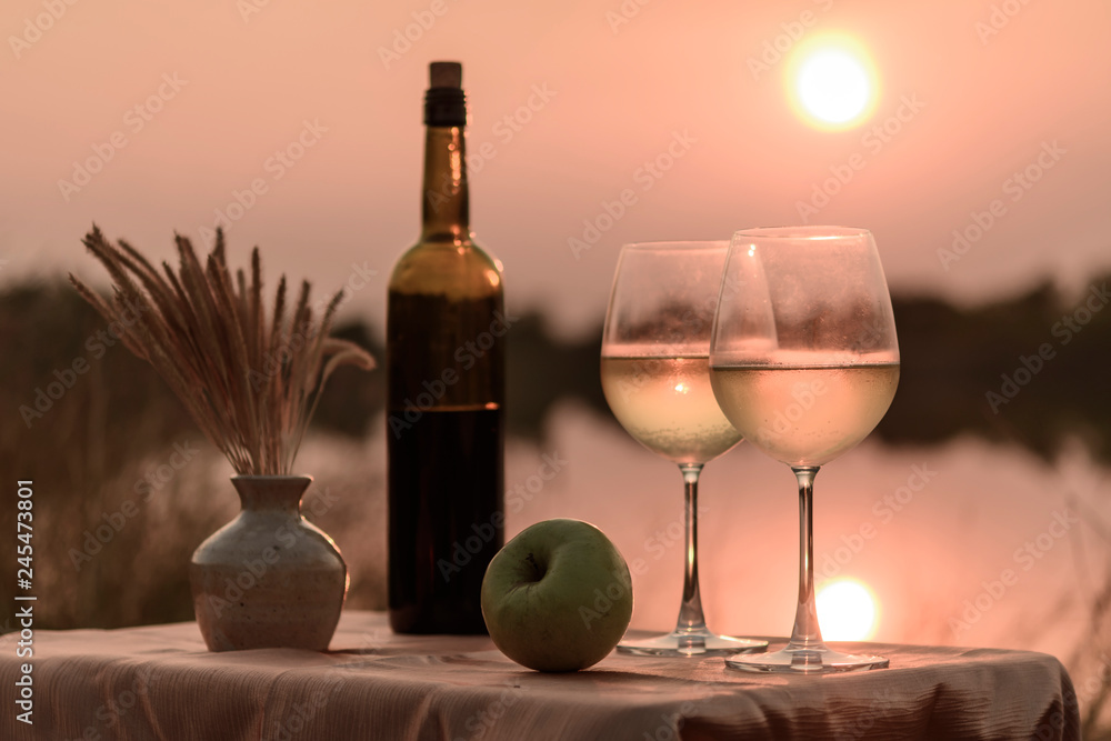 A romantic dinner in summer on a beach at sunset with two glasses of white wine A romantic dinner in summer on a beach at sunset with two glasses of white wine