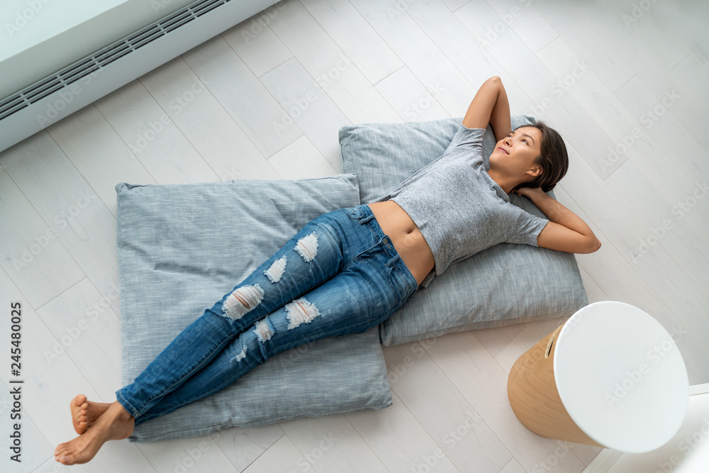 Home lifestyle happy Asian woman relax lying down on living room floor pillows relaxing contemplative looking at windows. New condo apartment satisfaction homeowner young girl enjoying house. - obrazy, fototapety, plakaty 