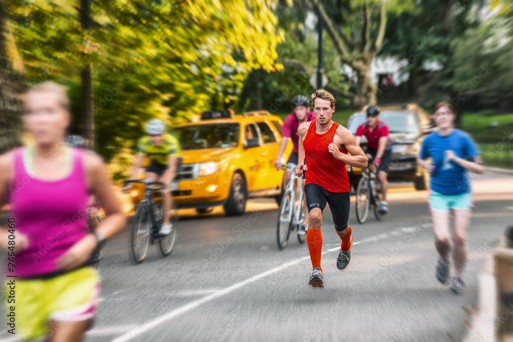 Fototapeta premium Runner athlete man running in run marathon race in Central Park New York city. People crowd jogging in street urban active lifestyle. Motion blur focus on one person.