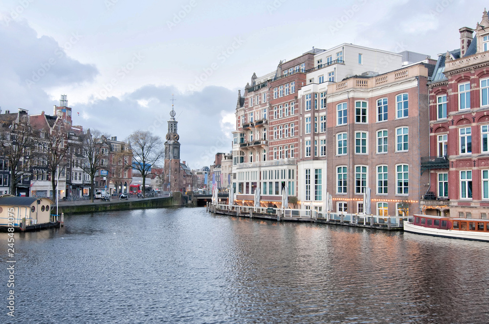 The Mint tower (Munttoren) with the Amstel river in Amsterdam, the Netherlands, view from Halvemaansbrug bridge.