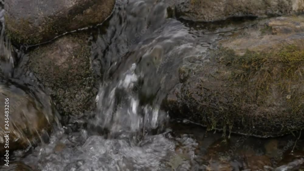 small mountain creek in winter season. Gurgling water stream over stones and boulders small mountain creek in winter season. Gurgling water stream over stones and boulders
