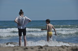 Children, siblings playing on the sea shore. They jumping in the waves.