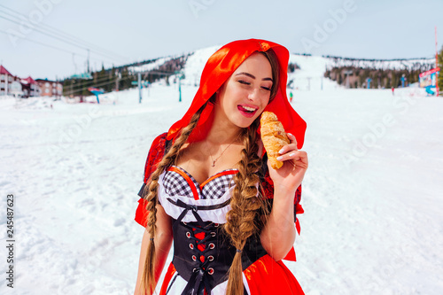 Little Red Riding Hood with wicker basket and kruasan on the snowy winter slope photo