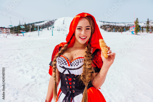 Little Red Riding Hood with wicker basket and kruasan on the snowy winter slope photo