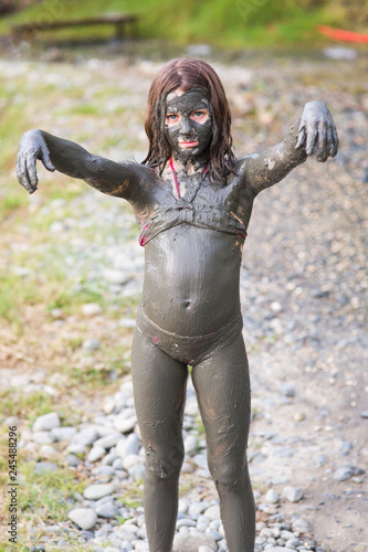 girl in a swimsuit in a mud mask on the whole body depicts a zombie