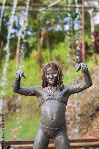 girl in a swimsuit in a mud mask on the whole body depicts a zombie