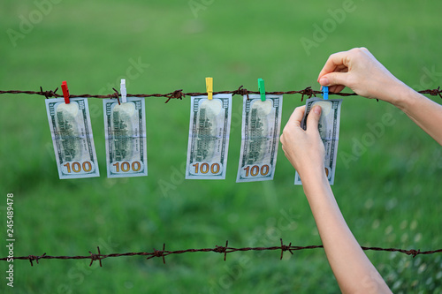 Money Laundering. Money Laundering US Dollar Hung Out To Dry. 100 Dollar Bill Hanging On Rusty Barbed Wire photo