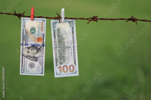 Money Laundering. Money Laundering US Dollar Hung Out To Dry. 100 Dollar Bill Hanging On Rusty Barbed Wire photo