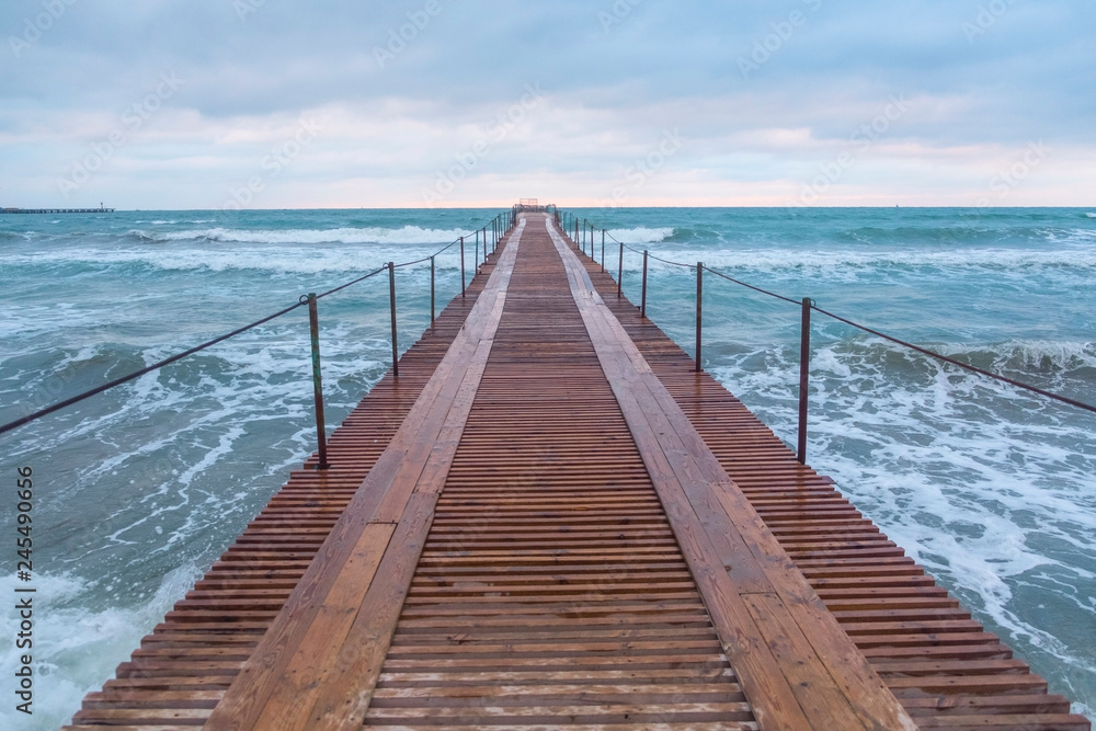 Wooden pier in the sea. Beautiful waves at sunset. Wooden pier in the sea. Beautiful waves at sunset.