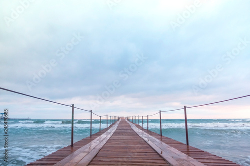 Wooden pier in the sea. Beautiful waves at sunset.