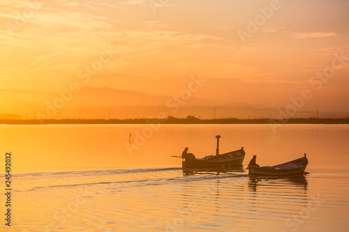 Two boats sailing through Albufera in Valencia at sunset