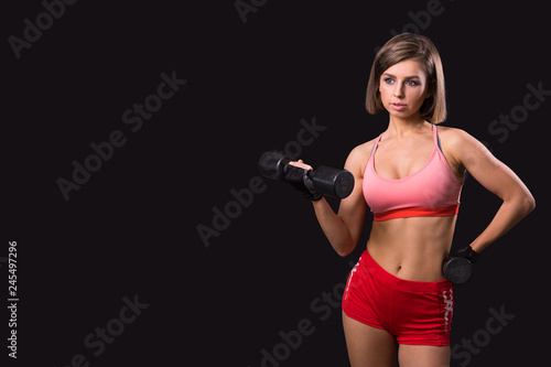 Beautiful young woman workout with dumbbell over gray background