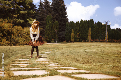 Beautiful girl in a hat in a vintage dress walking in a Summertime park photo