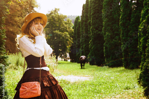 Beautiful girl in a hat in a vintage dress walking in a Summertime park photo