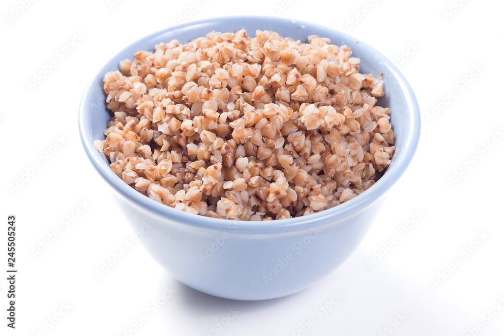 Boiled buckwheat in blue deep blue plate on white background with shadow Boiled buckwheat in blue deep blue plate on white background with shadow