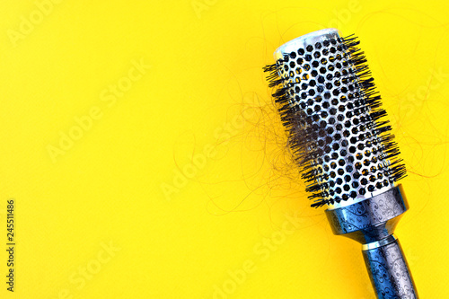 Hair loss concept with hairbrush and hair on it. Mixed bristle round brush with hairs. Hair problem of hair fall. Background with copy space.