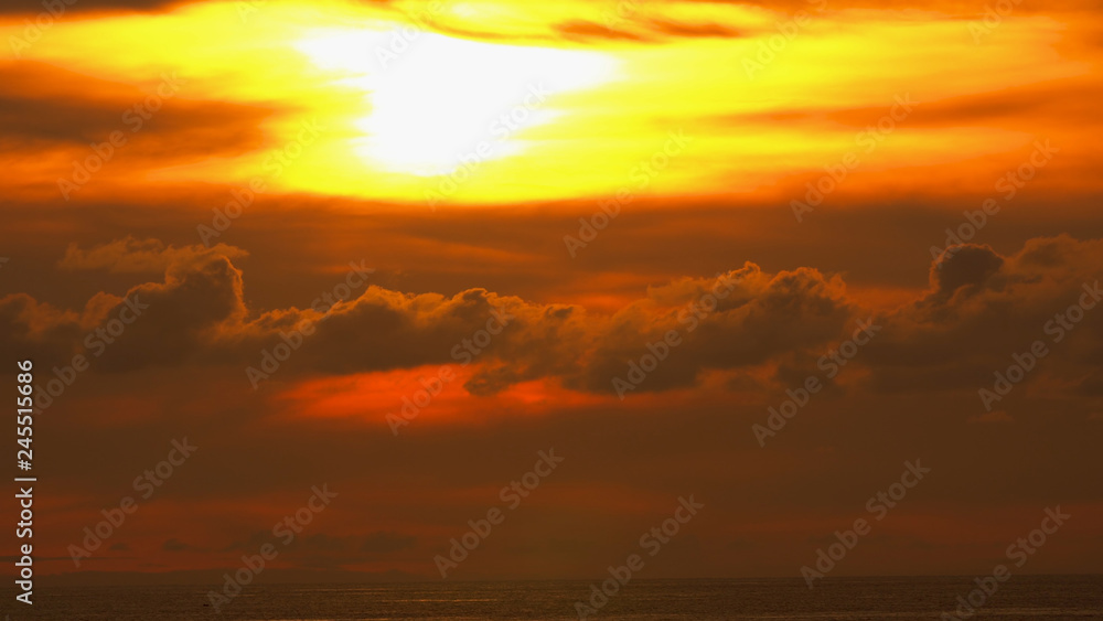 Bright red sunset in the clouds against the background of the sea. Beautiful picturesque sea view in the evening