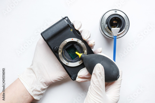 Close-up of mirrorless digital APS-C dirty camera matrix sensor cleaning and maintenance with swab, photographer cleaning photocamera on white background photo