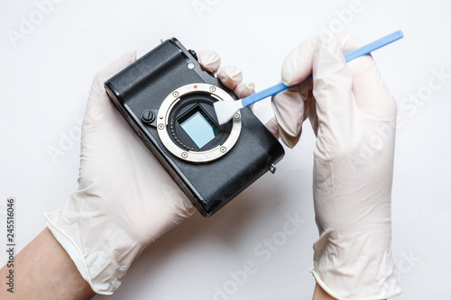 Close-up of mirrorless digital APS-C dirty camera matrix sensor cleaning and maintenance with swab, photographer cleaning photocamera on white background photo