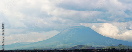 Distant view of Mount Nyiragongo, located in Virunga National Park, in the Democratic Republic of Congo (DRC). It is an active volcano with a lava lake. Mountain peak - landscape with clouds.