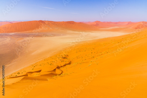 Tourist walking on the scenic dunes of Sossusvlei, Namib desert, Namib Naukluft National Park, Namibia