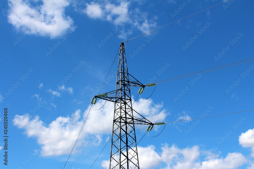 Electrical power line utility pole made of strong metal pipes with multiple electrical wires connected with glass insulators in front of cloudy blue sky background Electrical power line utility pole made of strong metal pipes with multiple electrical wires connected with glass insulators in front of cloudy blue sky background
