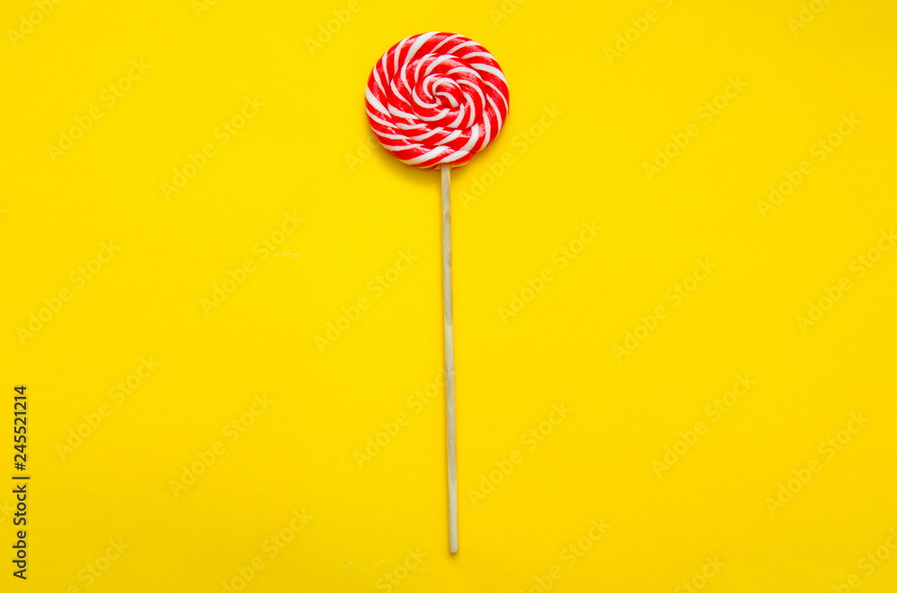 lollipop, a beautiful red and white striped round lollipop on a yellow background lollipop, a beautiful red and white striped round lollipop on a yellow background