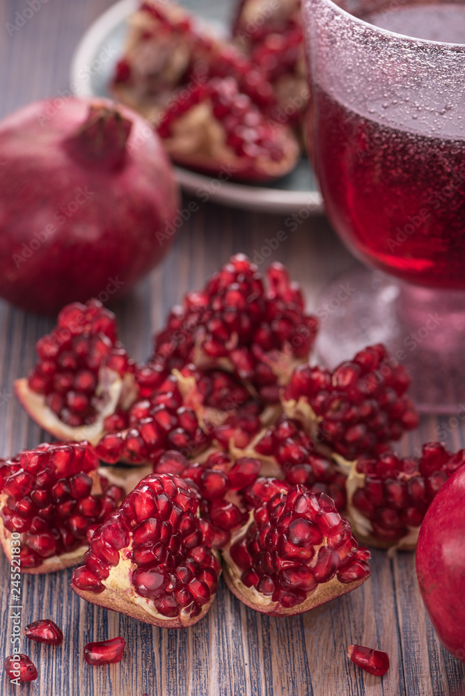 Pomegranate juice in a glass with fresh pomegranates around with scattered seeds on rustic wooden background 3 Pomegranate juice in a glass with fresh pomegranates around with scattered seeds on rustic wooden background 3