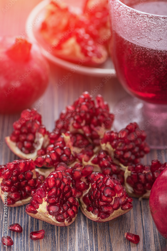 Pomegranate juice in a glass with fresh pomegranates around with scattered seeds on rustic wooden background toned Pomegranate juice in a glass with fresh pomegranates around with scattered seeds on rustic wooden background toned