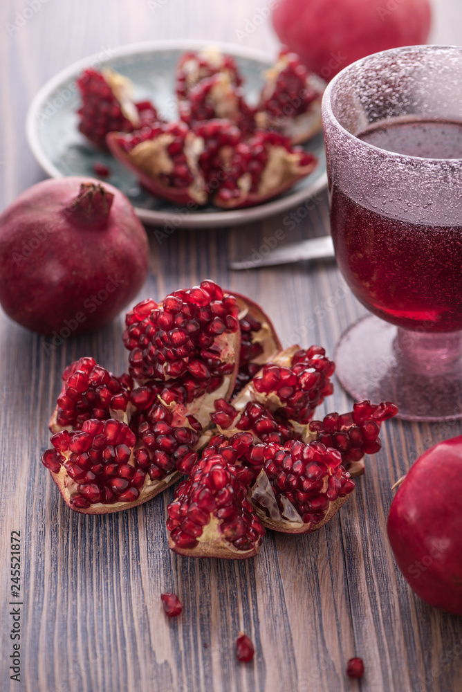 Pomegranate juice in a glass with fresh pomegranates around with scattered seeds on rustic wooden background 5 Pomegranate juice in a glass with fresh pomegranates around with scattered seeds on rustic wooden background 5