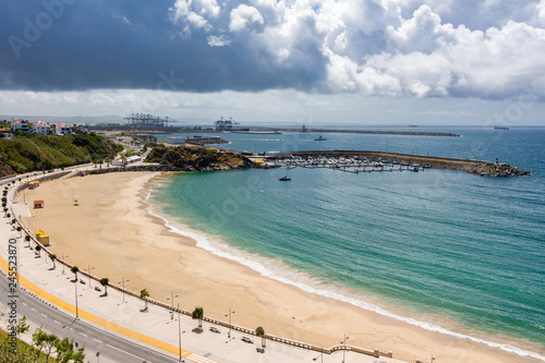 Panorama view over Vasco da Gama beach in town of Sines. Turquoise water. Moody sky, clouds.
