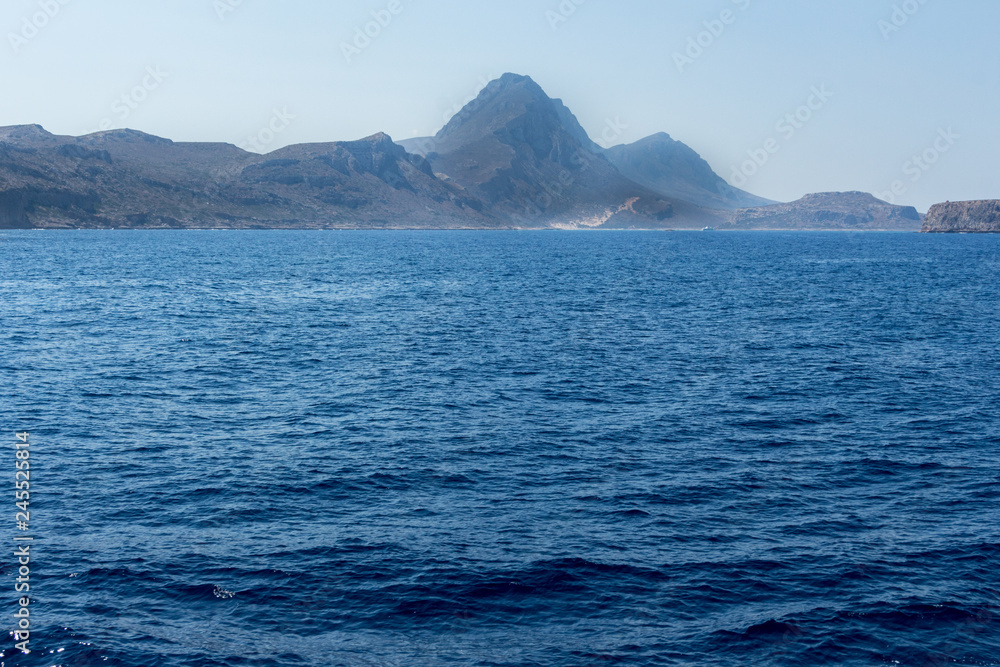 View over mountains from a boat. Deep dark blue water in the foreground. Mediterranean Sea.