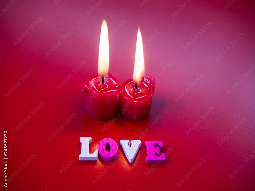 Concept of love Red candles lit and the word love with a red background Concept of love Red candles lit and the word love with a red background