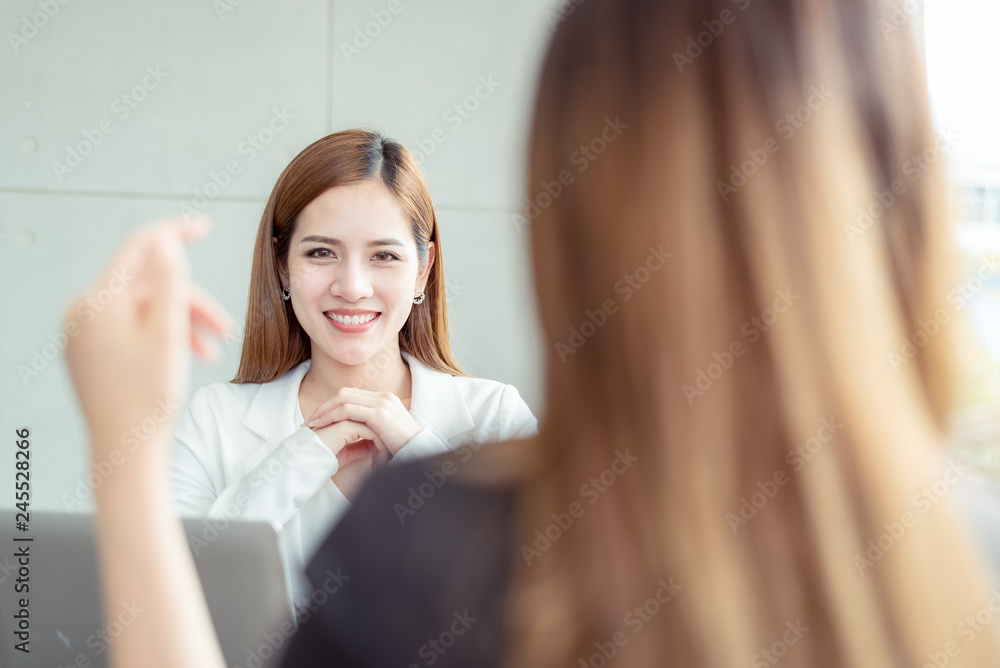 Closed up of Two confident asian business women entrepreneurs beautiful smile young financial assistant business woman while talking with colleague team at the modern office interior. Closed up of Two confident asian business women entrepreneurs beautiful smile young financial assistant business woman while talking with colleague team at the modern office interior.
