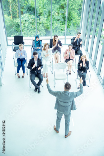 Business people multiethnic team smile and sitting diversity seminar conference meeting while audience applauding speaker presentation business at modern office hall.Seminar business concept. top view