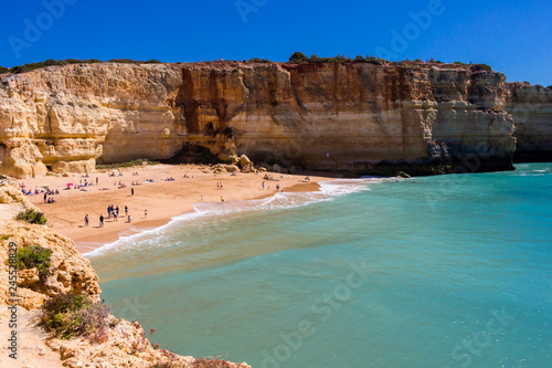 View over the Benagil beach, cliffs and turquoise ocean. People on the beach enjoying on a beautiful, sunny day.