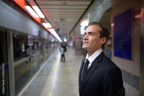 Young businessman smiling and waiting train at platform