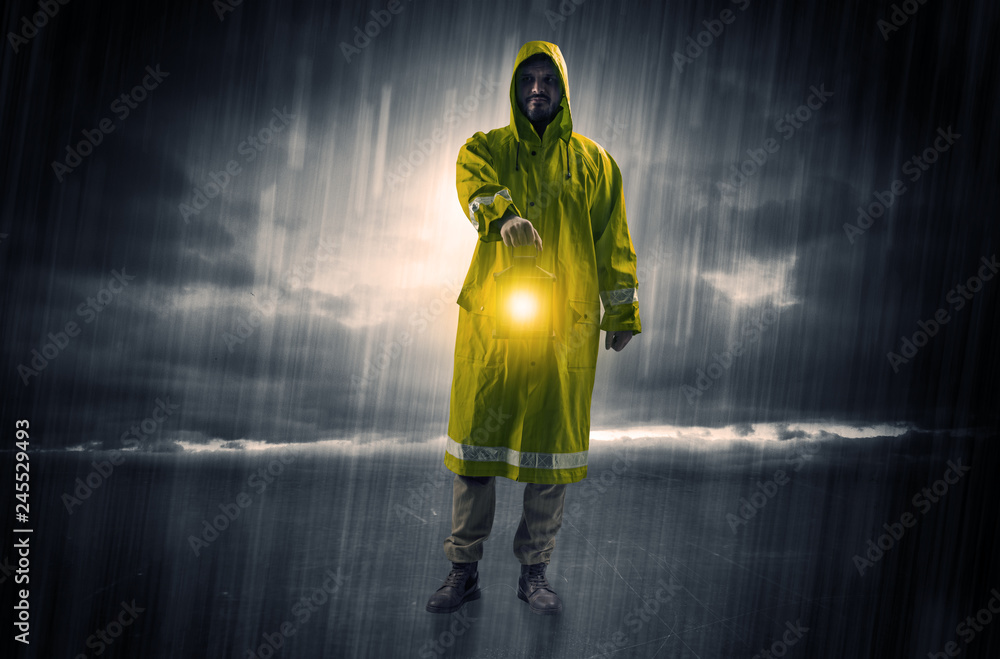 Fototapeta premium Raincoated man walking in storm with glowing lantern in his hand 