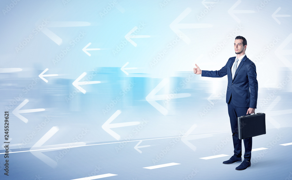 Young businessman hitchhiking near the city with arrows around concept Young businessman hitchhiking near the city with arrows around concept