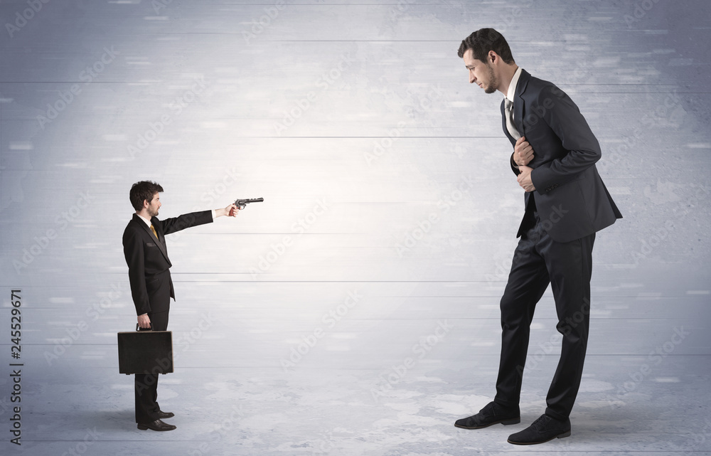 Tiny businessman with gun shooting giant fearful businessman
