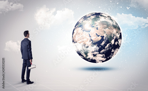 Businessman standing with his back with objects in his hand and looking at the globe  courtesy of NASA 