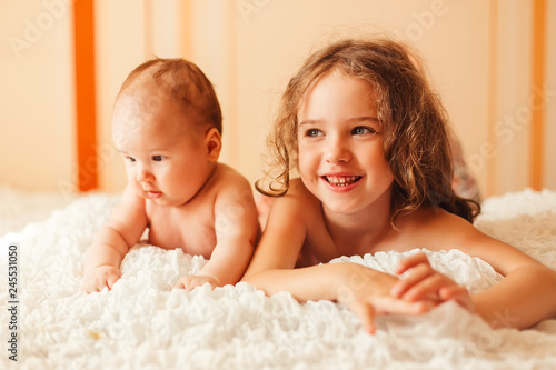 IClose up portrait of cute adorable baby girl with infant brother lying on bed photo