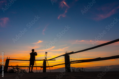 Photographer taking a photo of sunset in silhoustte. Sunset landscape.