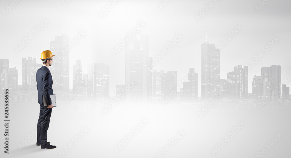 Young supervisor architect standing and looking at a big city panorama
Young supervisor architect standing and looking at a big city panorama
