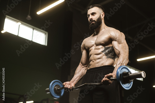 Handsome strong athletic men pumping up muscles workout barbell curl bodybuilding concept background