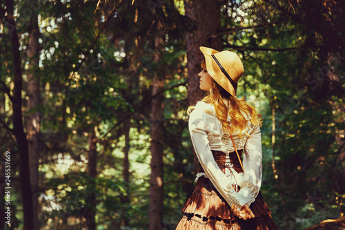 Beautiful girl in a hat in a vintage dress walking in a Summertime park photo